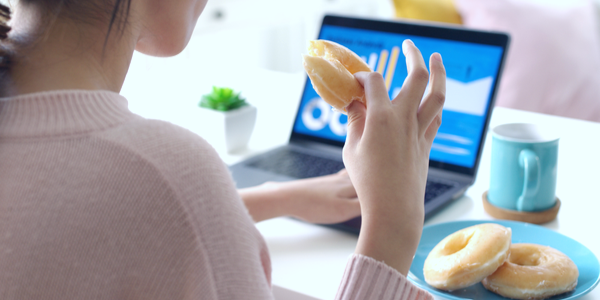 woman-mindlessly-eating-donuts-at-desk